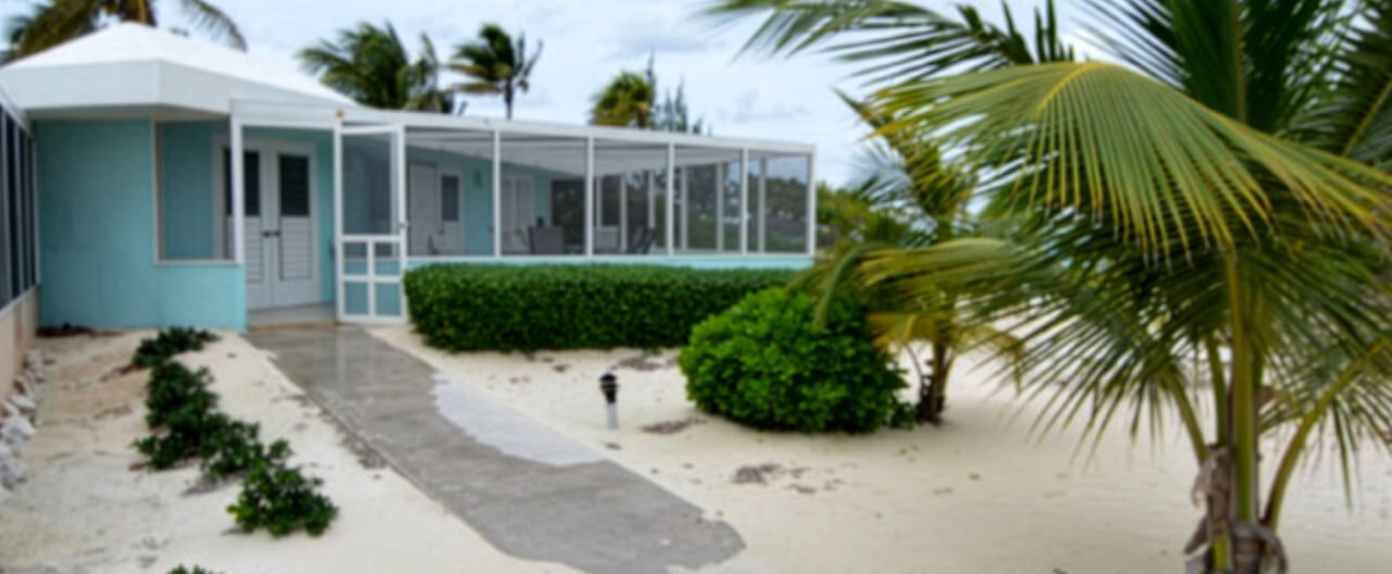 SeaRendipity cottage exterior framed by palms and a sandy garden path