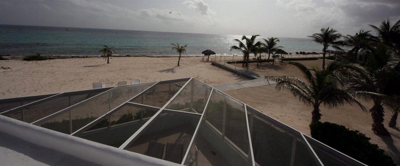 Elevated view over the porch enclosure to the palm-lined beach and turquoise sea